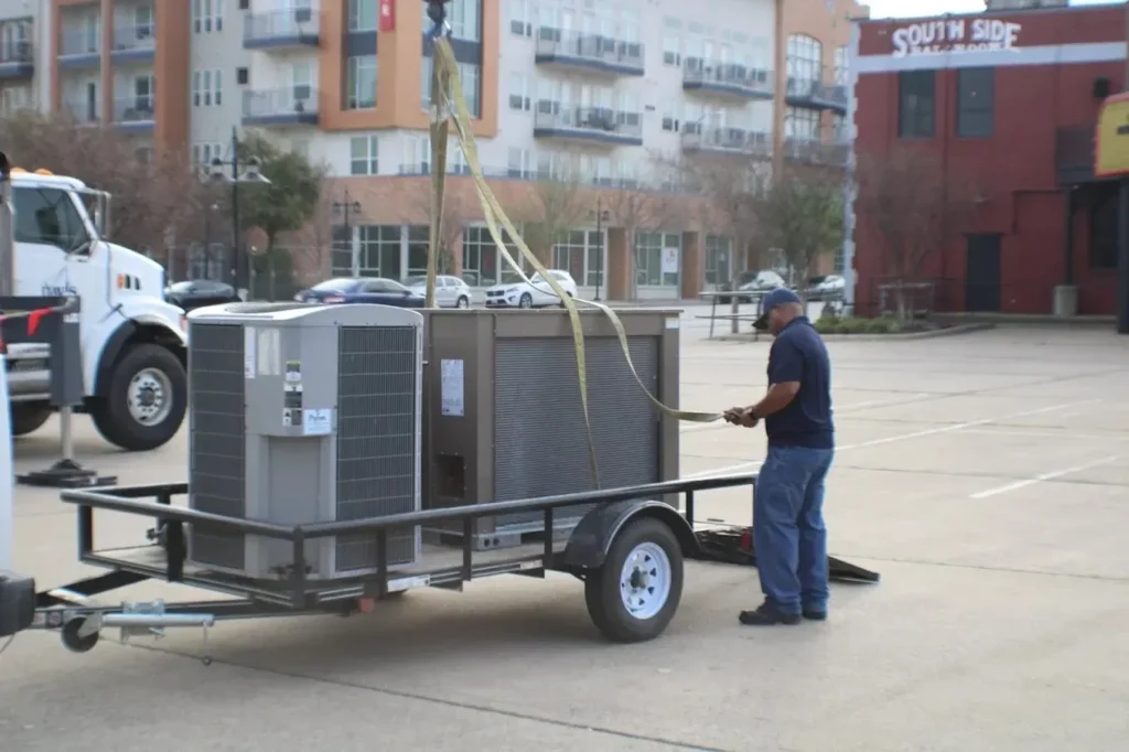 Why Is My AC Not Cooling? Troubleshooting Guide 1 A man securing an air conditioning unit on a trailer in an urban setting.